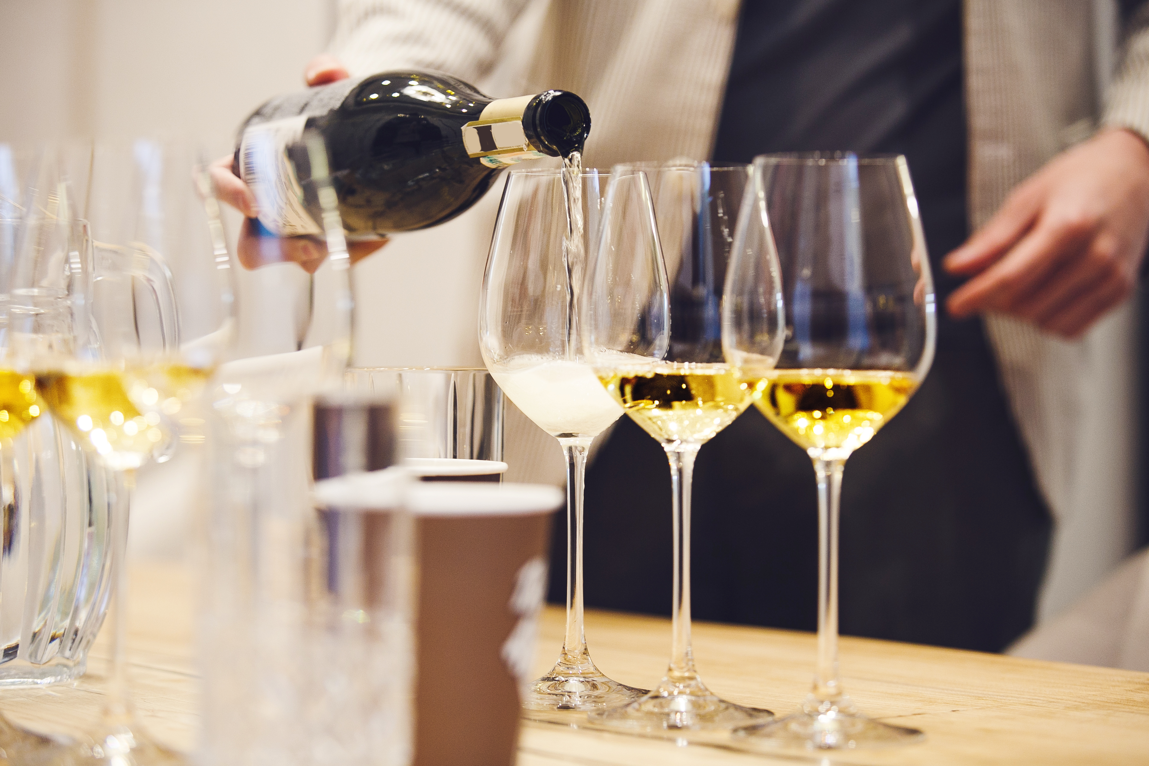 Close up, bartender pouring sparkling wine to the glass during sommelier degustation.